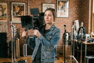 Étudiante en école de cinéma tenant une caméra professionnelle dans un studio de tournage